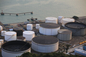 Circular industrial storage and water-management structures beside a coastal facility