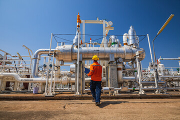 Terminal operator walking beside pumps, valves and petroleum transfer pipework